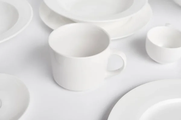 Selektiver Fokus verschiedener Teller, Schüssel und Tasse auf weißem Tisch — Stockfoto