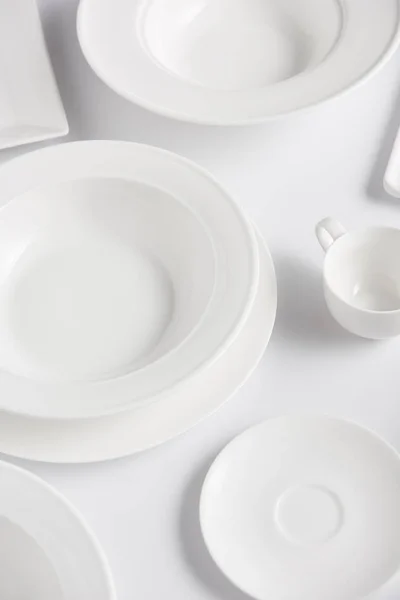 Blick auf verschiedene Teller und Tassen auf weißem Tisch — Stockfoto