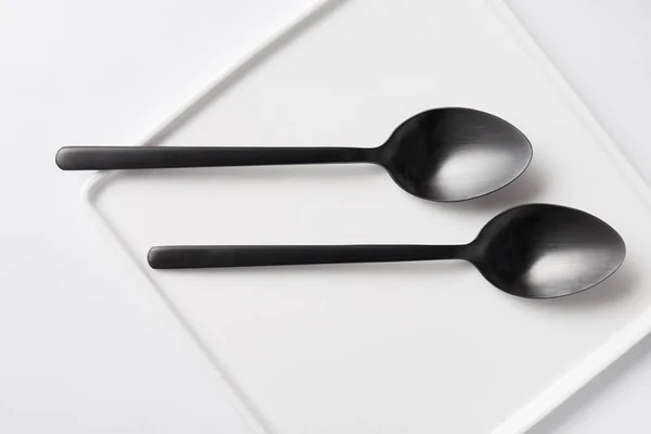 Vista superior de dos cucharas y plato en mesa blanca, concepto minimalista - foto de stock