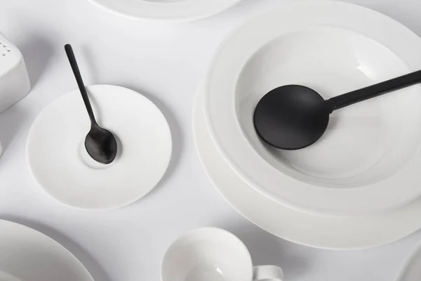 Close up image of various plates, spoon, cup and salad spoon on white table — Stock Photo