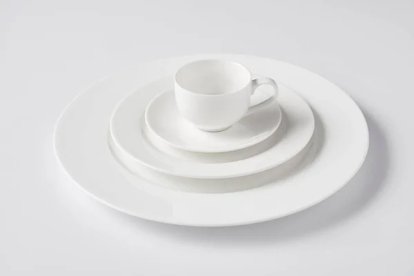 Selective focus of cup on stack of different plates on white table — Stock Photo