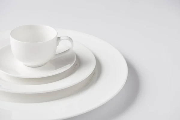 Immagine ravvicinata di tazza su pila di piastre diverse su tavolo bianco — Foto stock