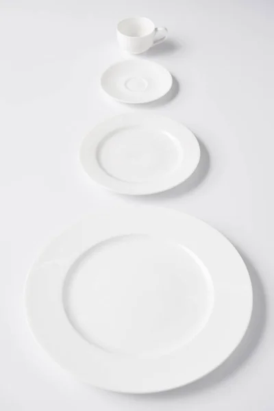 Selective focus of arranged various plates and cup on white table — Stock Photo