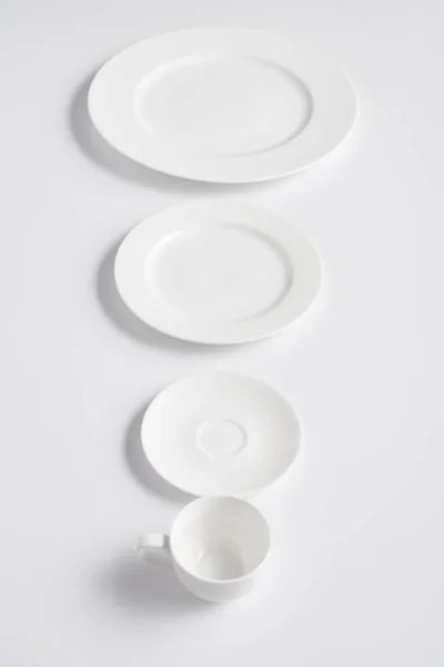 Selective focus of arranged various plates and cup on white table — Stock Photo