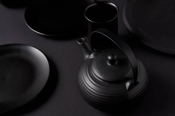 Foyer sélectif de théière noire, tasse et assiettes sur table noire — Photo de stock