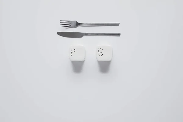 Top view of fork, knife, saltcellar and pepper caster on white table, minimalistic concept — Stock Photo