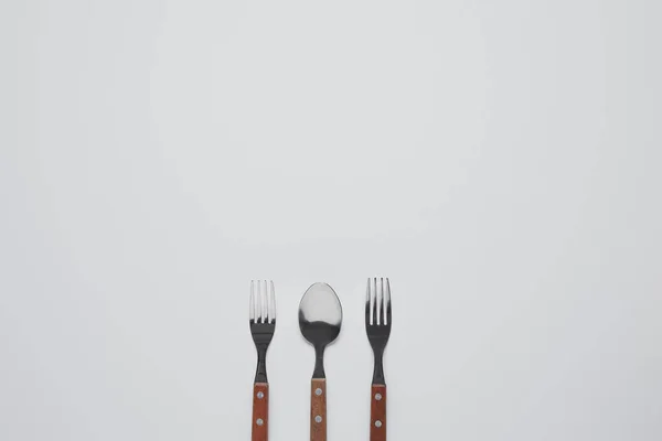 Top view of spoon between forks on white table, minimalistic concept — Stock Photo