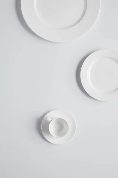 Elevated view of different plates and cup on white table — Stock Photo