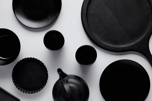 Top view of black teapot, plates, bowl, baking dish and cups near tray on white table — Stock Photo