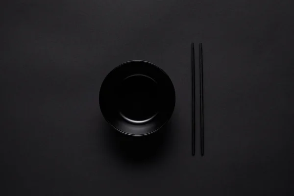 Top view of black and chopsticks on black table, minimalistic concept — Stock Photo