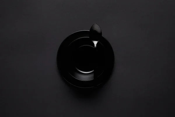 Top view of black bowl and spoon on black table, minimalistic concept — Stock Photo