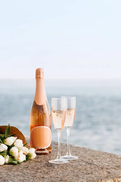 Close-up view of beautiful bouquet of flowers and champagne in glasses and bottle on embankment — Stock Photo