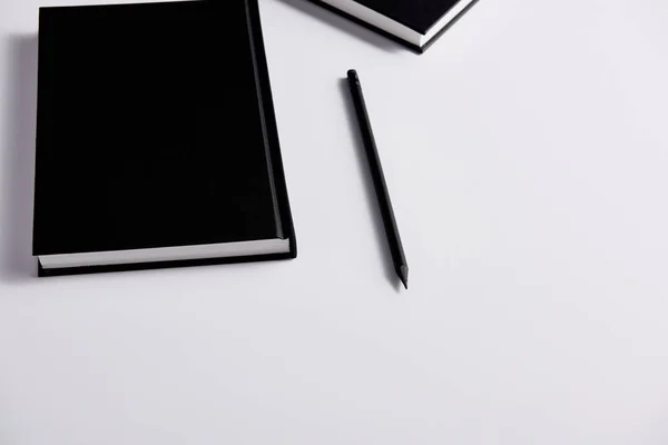Close-up shot of black hard cover notebooks with pencil on white surface — Stock Photo
