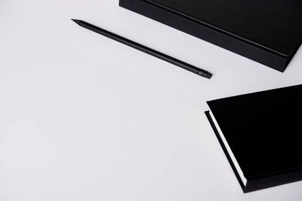 Close-up shot of black hard cover notebooks with pencil on white tabletop — Stock Photo