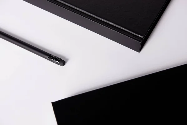 Close-up shot of black notebooks with pencil on white surface for mockup — Stock Photo