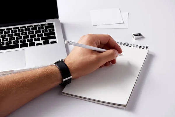 Tiro recortado do homem que escreve no caderno durante o trabalho na superfície branca — Fotografia de Stock