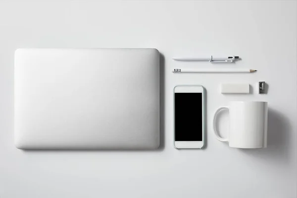 Ansicht von Laptop mit Smartphone und Bürozubehör auf weißer Tischplatte für Attrappen — Stockfoto