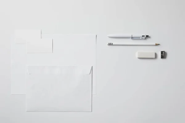 Vue de dessus de divers objets en papier et fournitures de bureau sur surface blanche pour la maquette — Photo de stock