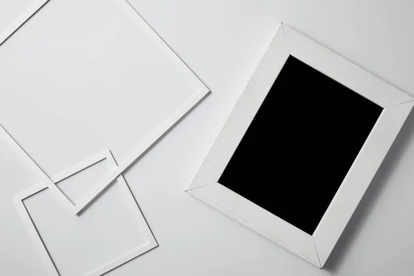 Vista superior de quadros quadrados com quadro negro em branco na superfície branca para mockup — Fotografia de Stock