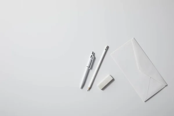 Top view of envelope with pen and pencil on white surface for mockup — Stock Photo