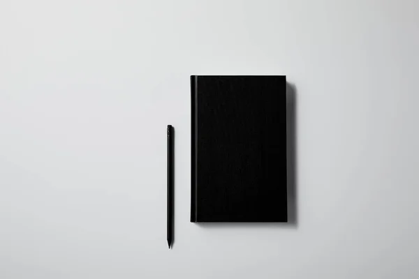 Top view of black notebook with pencil on white surface for mockup — Stock Photo