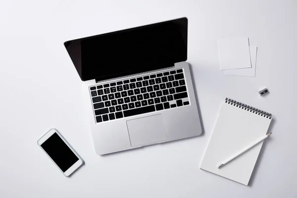 Vue de dessus du lieu de travail avec ordinateur portable et smartphone sur la table blanche pour la maquette — Photo de stock