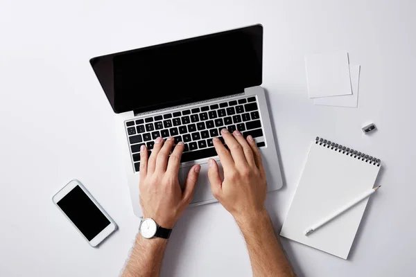 Tiro cortado de homem digitando com laptop no local de trabalho na superfície branca para mockup — Fotografia de Stock