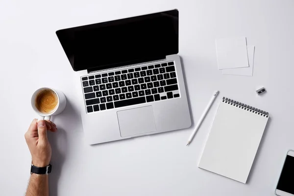 Cropped shot of man folding coffee cup at workplace with supplies on white surface for mockup — Stock Photo