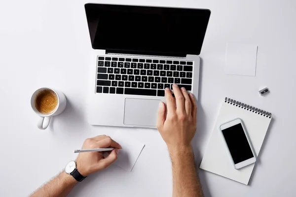 Tiro cortado do homem que trabalha com laptop no local de trabalho na superfície branca para o mockup — Fotografia de Stock