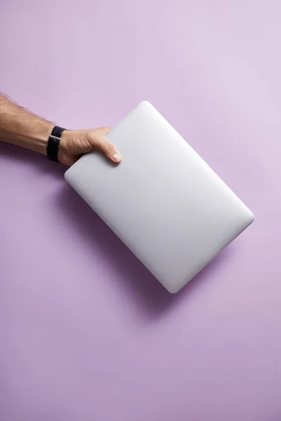 Cropped shot of man holding folded laptop over pink surface — Stock Photo