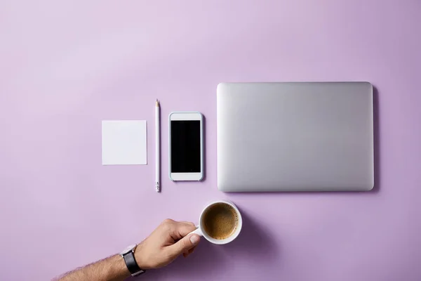 Cropped shot of man folding coffee cup at workplace on pink surface for mockup — Stock Photo