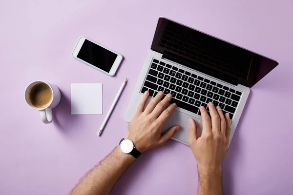 Plan recadré de l'homme en utilisant un ordinateur portable sur le lieu de travail sur la surface rose pour la maquette — Photo de stock