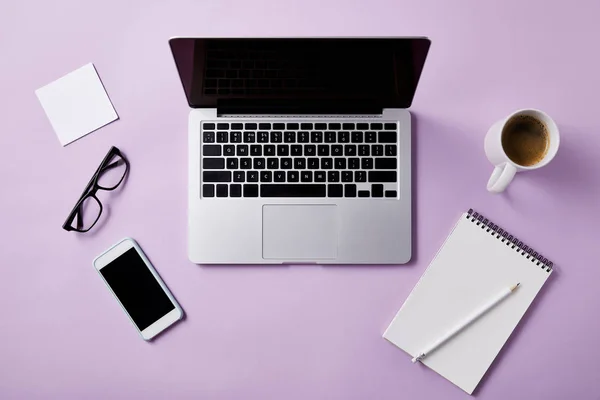 Ansicht des Arbeitsplatzes mit Laptop und Smartphone auf rosa Tischplatte zum Nachmachen — Stockfoto