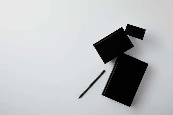 Top view of black notebooks with business card and pencil on white surface for mockup — Stock Photo