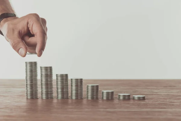 Cropped image of man stacking last coin on wooden table, saving concept — Stock Photo