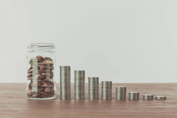 Pot avec des pièces et des piles de pièces sur table en bois, concept d'économie — Photo de stock