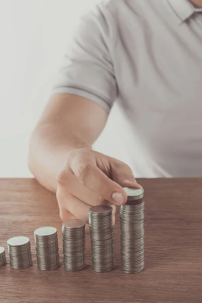 Cropped image of man stacking coins on wooden table, saving concept — Stock Photo