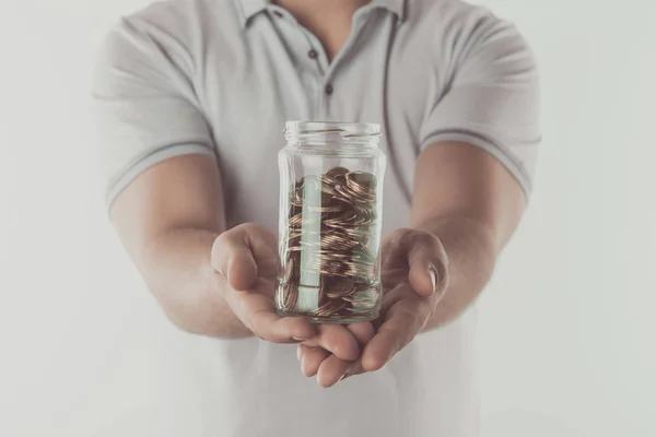 Обрезанный образ человека, показывающий банку монет в руках изолированных на белом, сохраняя концепцию — стоковое фото