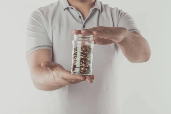Imagem cortada do homem segurando frasco de moedas em mãos isoladas em branco, conceito de poupança — Fotografia de Stock