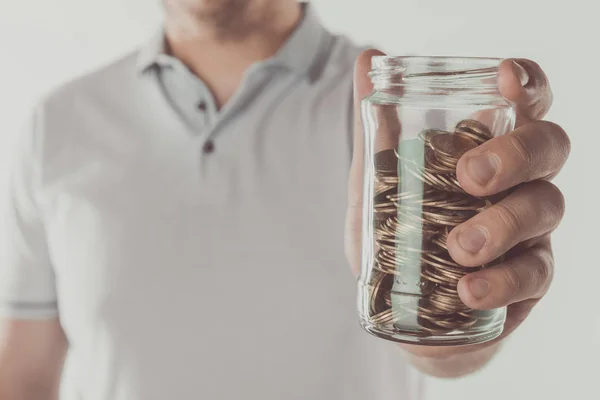 Imagen recortada del hombre sosteniendo frasco de monedas aisladas en blanco, concepto de ahorro - foto de stock