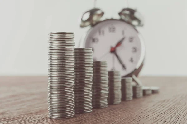 Pilhas de moedas e despertador na mesa, economizando conceito — Fotografia de Stock