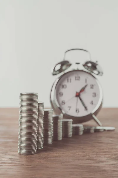 Stacks of coins and alarm clock on wooden table, saving concept — Stock Photo