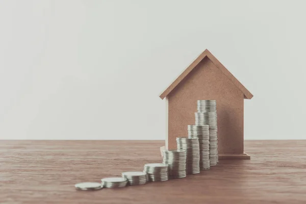 Stacks of coins and small house on brown wooden tabletop, saving concept — Stock Photo