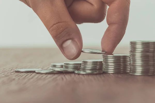 Cropped image of man stacking coins on brown wooden table, saving concept — Stock Photo