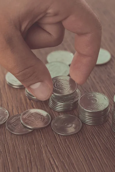 Imagem cortada do homem empilhando moedas ucranianas na mesa, economizando conceito — Fotografia de Stock