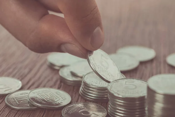 Cropped image of man stacking ukrainian coins on wooden table, saving concept — Stock Photo