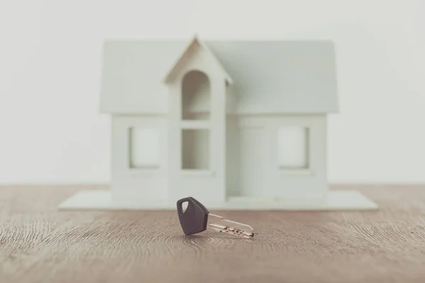 Ключ и небольшой деревянный дом на столешнице, концепция экономии — стоковое фото