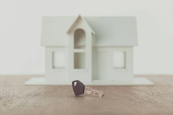 Chave e pequena casa de madeira na mesa, economizando conceito — Fotografia de Stock