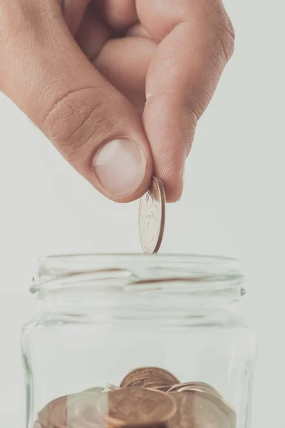 Imagen recortada del hombre poniendo moneda en frasco de vidrio aislado en blanco, concepto de ahorro - foto de stock