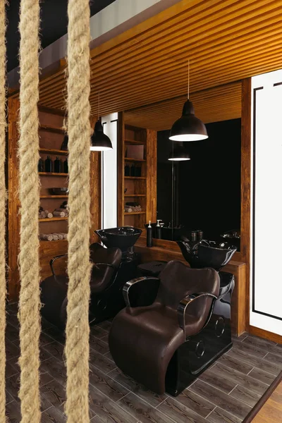 Close-up view of ropes and empty leather chairs and sinks in modern barbershop — Stock Photo